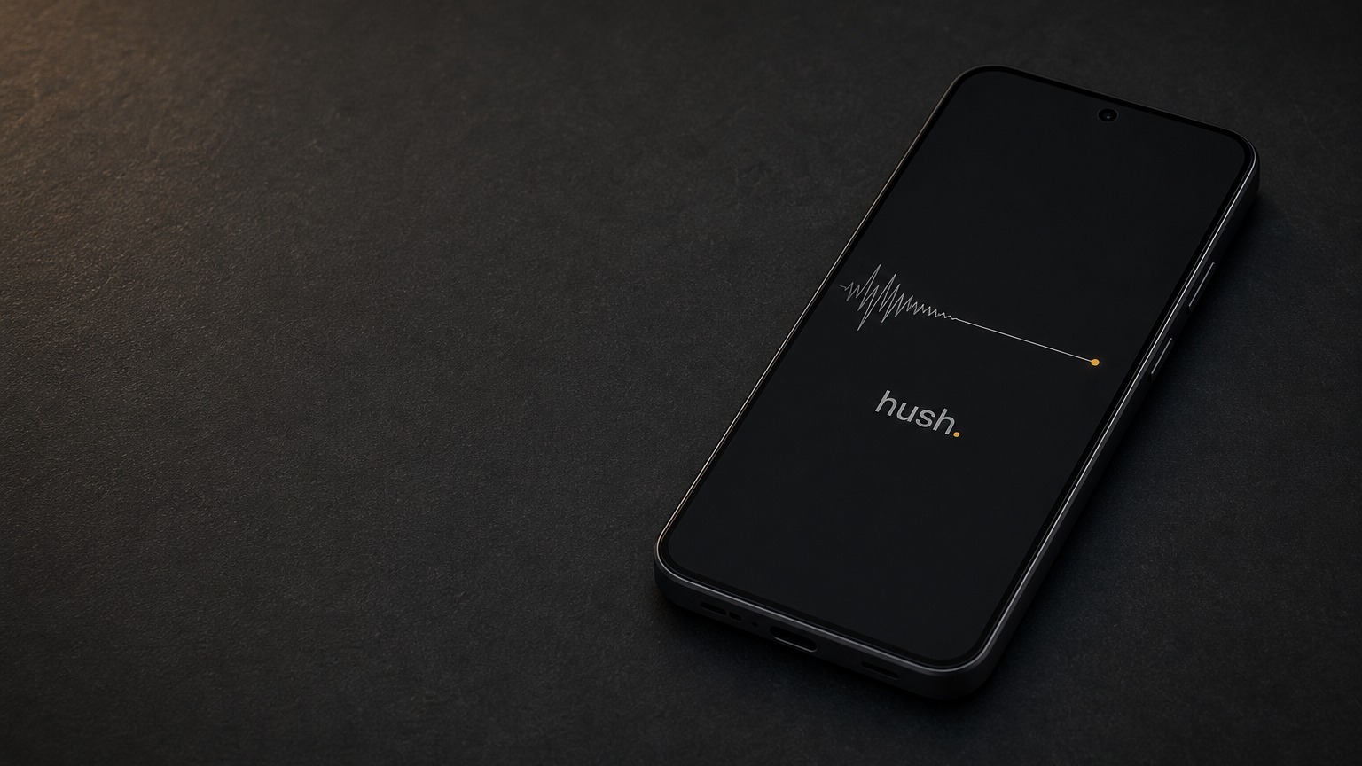 HushPhone on a dark desk, its screen showing a signal waveform flattening into a quiet line ending in an amber dot.